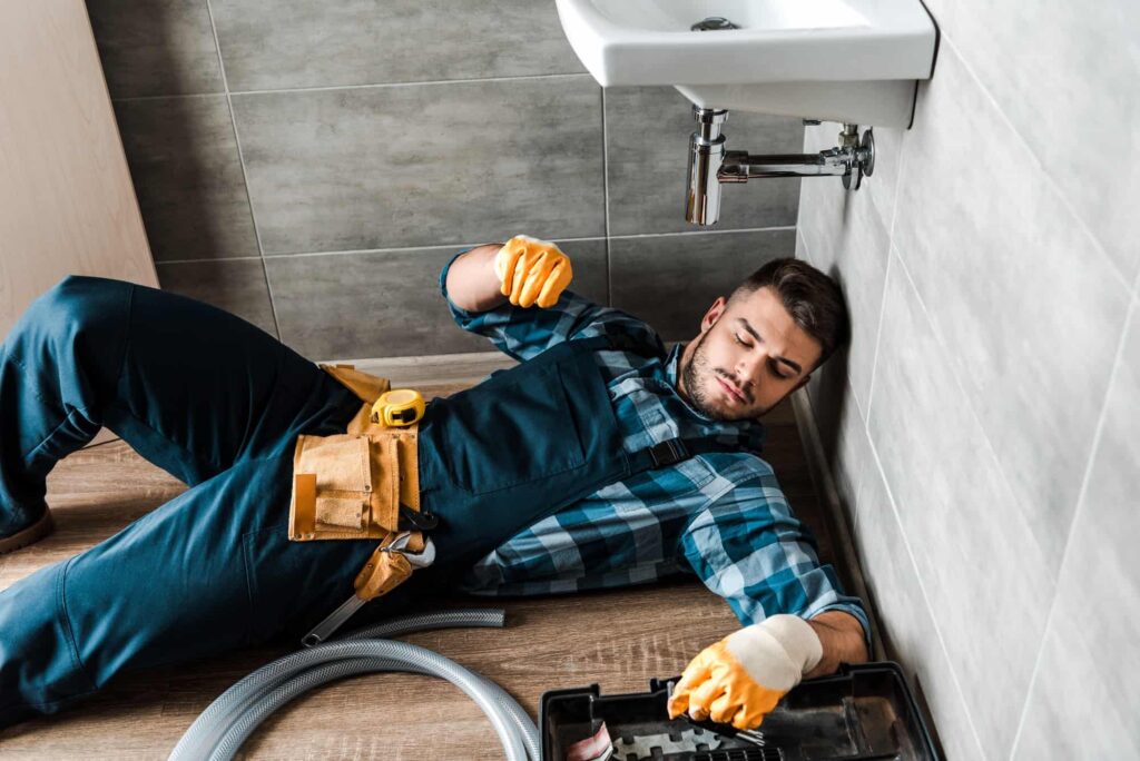 Bearded handyman lying on floor near toolbox in bathroom.jpg