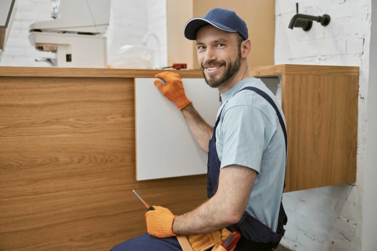 Cheerful male worker fixing cupboard door in kitchen.jpg